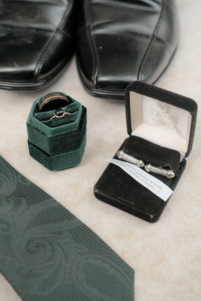 Wedding accessories including rings, cufflinks, and leather shoes with a textured tie.