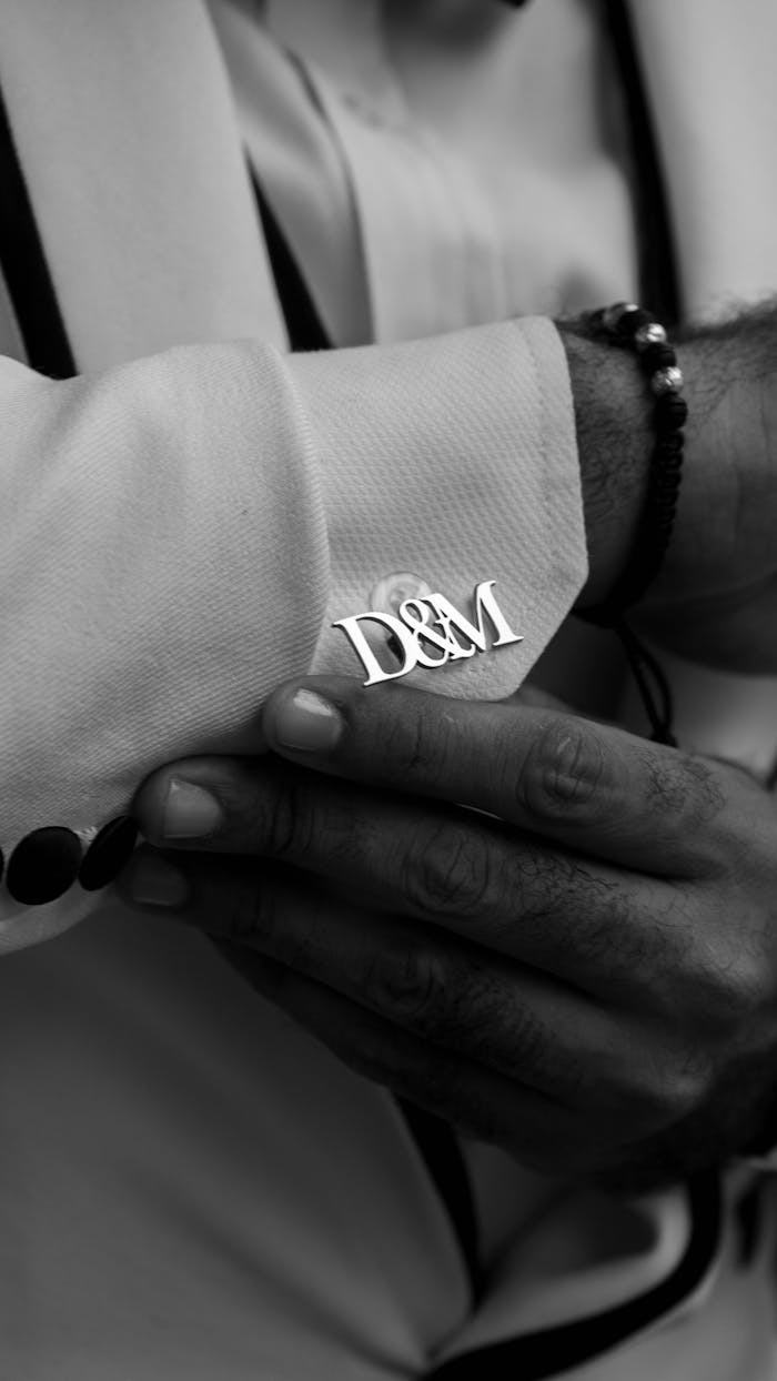 Black and white photo highlighting personalized cufflinks on a well-dressed man's sleeve.